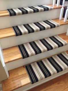 a set of stairs with black and white striped rugs on the bottom, along with wooden handrails