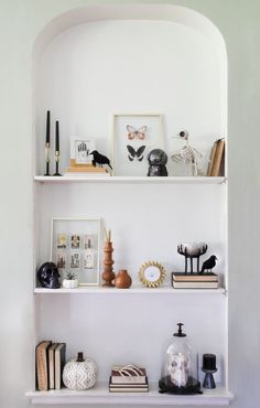 two white shelves with pictures and other items on them