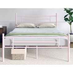 a pink metal bed frame with two pillows on the top and bottom, in front of a white wall