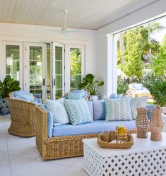 a living room with wicker furniture and blue cushions on the couches in front of glass doors