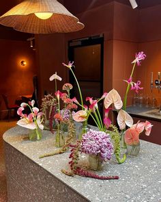 vases filled with flowers sitting on top of a counter next to a light fixture