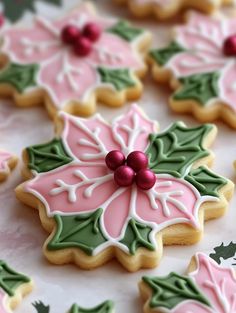 decorated cookies with holly and poinsettis on a white tableclothed surface