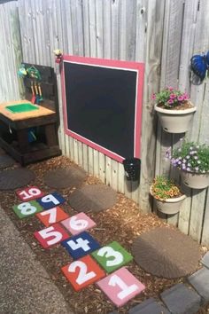 an outdoor play area with letters and numbers on the ground in front of a fence