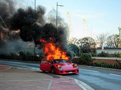 a red sports car is on fire in the street