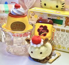 a hello kitty toy sitting on top of a table next to a cupcake and cell phone