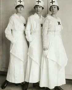 three women in nurses'uniforms standing next to each other with crosses on their heads