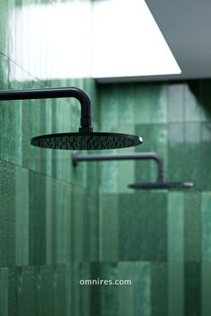 a green tiled bathroom with shower head and handset