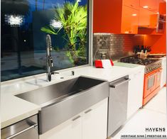 an orange and white kitchen with stainless steel sink, dishwasher, and oven