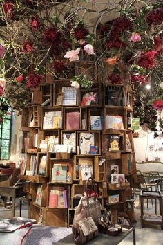 there is a book shelf with many books on it and flowers hanging from the ceiling