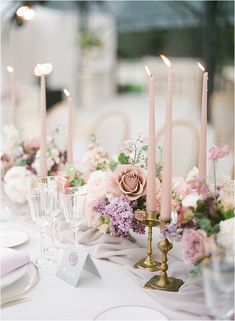 the table is set with pink and white flowers, candles, and place settings for dinner