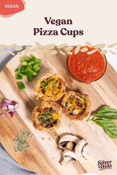 vegan pizza cups on a wooden cutting board with mushrooms, peppers and sauces