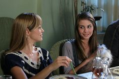 three people sitting at a table with food in front of them and one person holding a spoon