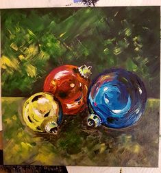 a painting of three different colored balls on a green surface with trees in the background