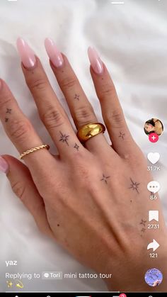 a woman's hand with two different tattoos on her fingers and one has a gold ring