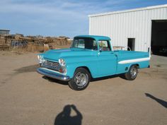 an old blue truck parked in front of a building