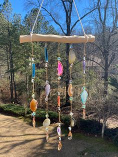 a wind chime hanging from the side of a road in front of some trees