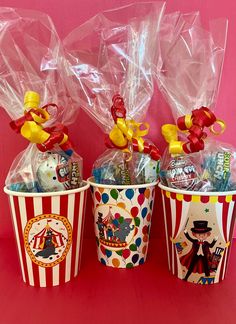 three buckets filled with candy and candies on a pink background, some wrapped in plastic