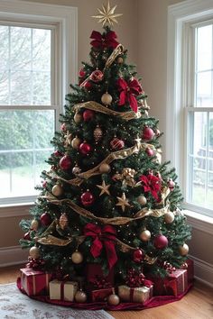 a decorated christmas tree in a living room with red and gold ornaments on the top