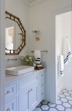 a white bathroom with blue cabinets and a large mirror above the sink, along with towels on the wall