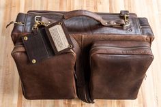 Fly in style next time you take a business trip or vacation with our limited edition brown Leather Flight Bag. This leather bag is finely handcrafted from the highest quality American Bison hides and 100% Made in USA. Any artisan that plays a part in handcrafting your flight bag adds their initials inside, making each flight bag unique. Each handmade vintage leather flight bag fits perfectly in an overhead compartment of an airplane so you can travel quick and easy with this carry on bag. Not on Leather Briefcase With Leather Lining For Trips, Brown Bags With Leather Lining For Trip, Luxury Brown Rectangular Leather Backpack, Brown Leather Backpack With Rectangular Shape, Brown Rectangular Leather Backpack With Leather Handles, Brown Leather Backpack With Leather Handles, Luxury Brown Briefcase For On-the-go, Brown Leather Backpack With Luggage Sleeve For Trip, Luxury Leather Rectangular Backpack For Trips