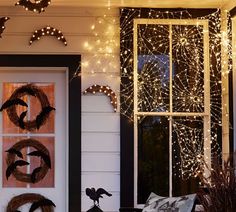 the front porch is decorated with wreaths, lights and decorations for halloween night time