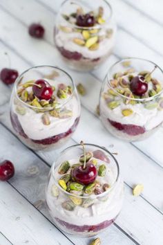 three desserts with cherries and pistachio in small glass dishes on a white table