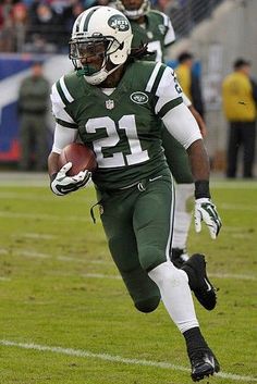 a football player running with the ball in his hand and people watching from the stands