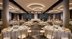 a banquet hall with tables and chairs set up for an event or function, all decorated in gold and white