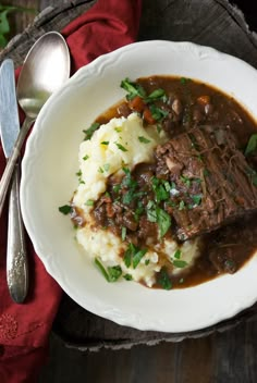 a white bowl filled with meat and mashed potatoes on top of a wooden table