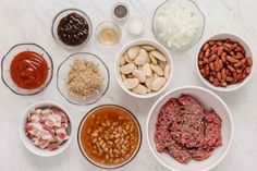 bowls filled with different types of food on top of a white counter next to sauces and seasonings