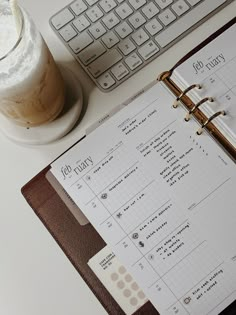 an open planner sitting on top of a desk next to a keyboard