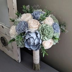 a bridal bouquet with blue and white flowers in front of an open door,