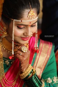 a woman in a green and pink sari with jewelry on her neck, holding her hands to her face