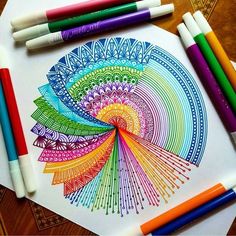 colored pencils and markers sitting on top of a paper with an image of a colorful wheel