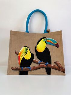 two toucans sitting on top of a branch in front of a canvas bag