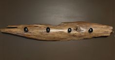 a piece of driftwood with five black beads hanging from it's center hole