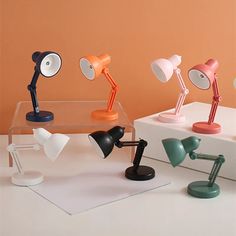 three desk lamps sitting on top of a white table next to each other and one lamp has a black base