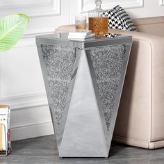 a glass side table with silver glitter on it and a plant in the corner next to it