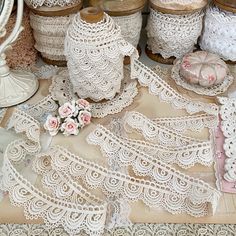 several different types of laces and other items on a table with pink flowers in vases