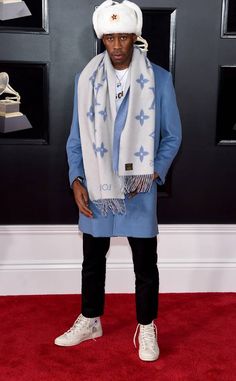 a man standing on top of a red carpet wearing a white hat and blue coat