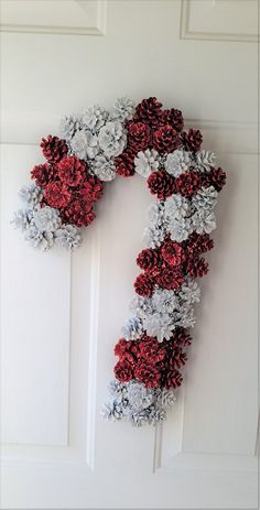 a wreath made out of red and white flowers hanging on the side of a door