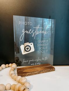 a wooden block with a camera on it next to some beads and a sign that says, photo guestbook