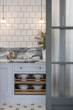 a kitchen with marble counter tops and white tile backsplashing, along with pots and pans