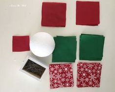 some red and green pieces of fabric next to a small white object on a table