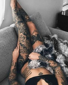 a woman laying on top of a couch covered in tattoos