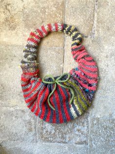 a multicolored knitted bag hanging on the wall next to a tile floor