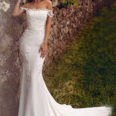 a woman in a wedding dress leaning against a stone wall