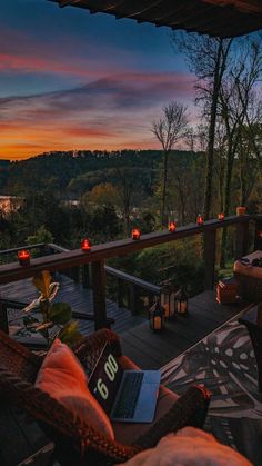 a laptop on a patio with candles lite up in the background at sunset or dawn