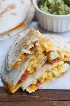 two quesadillas stacked on top of each other next to a bowl of guacamole