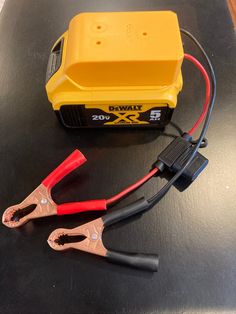 an orange and black battery on top of a table next to two red and black wires